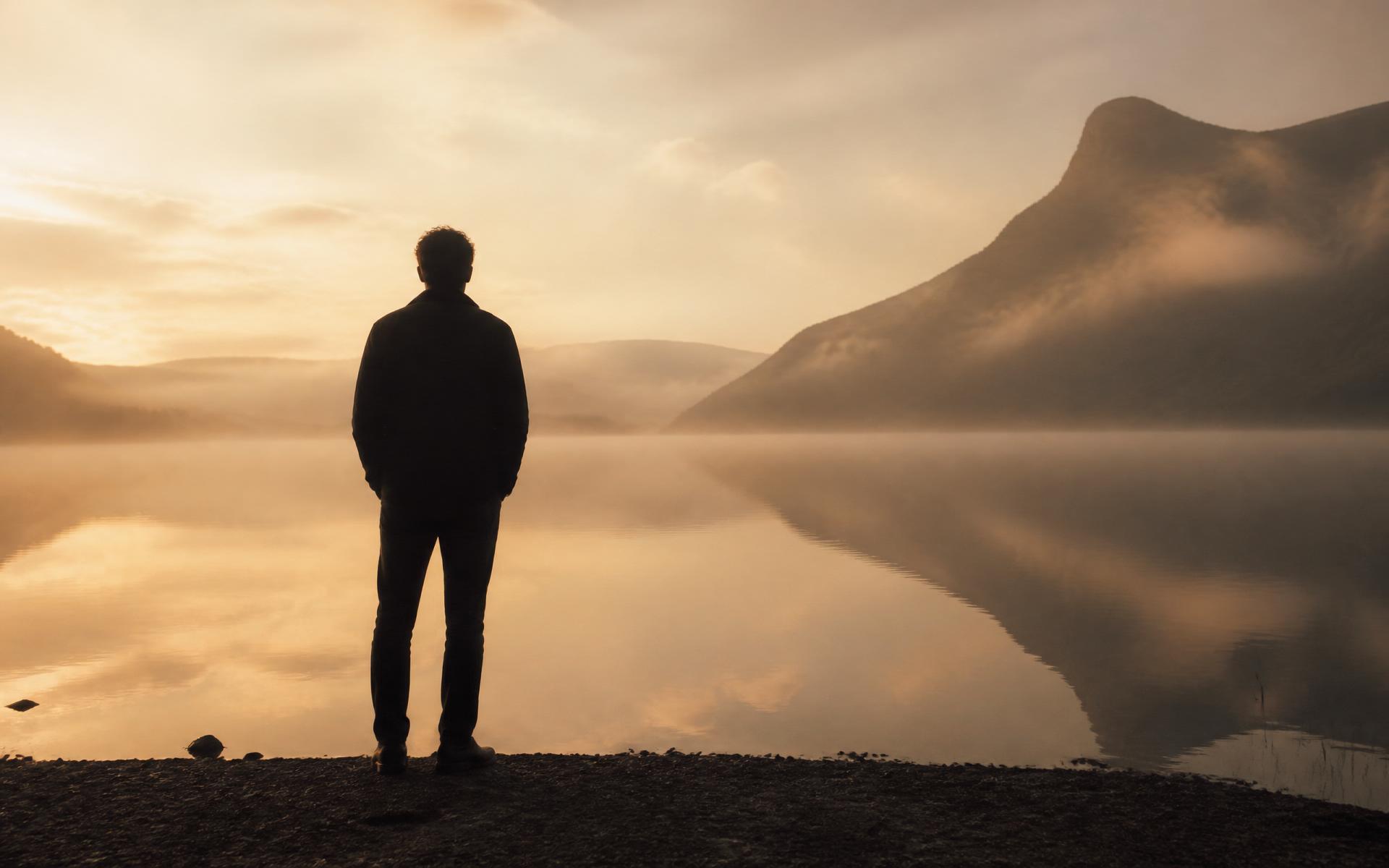 Silhouette seorang lelaki merenung tasik yang tenang